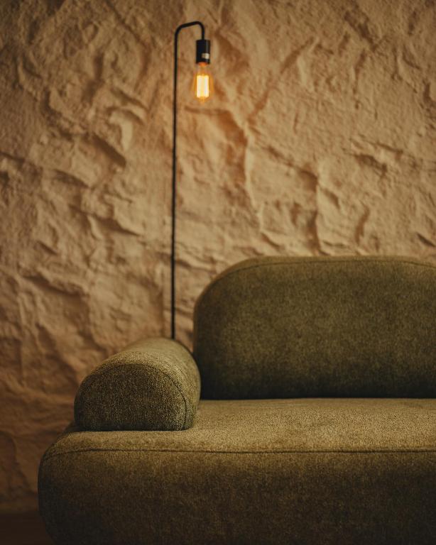 Green velvet sofa against textured stone wall