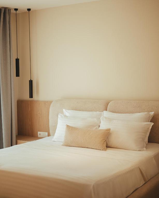 Bed detail with layered white pillows and pendant lights